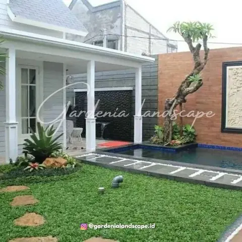 Kolam di samping teras rumah putih, dengan taman rumput dan batu pijakan