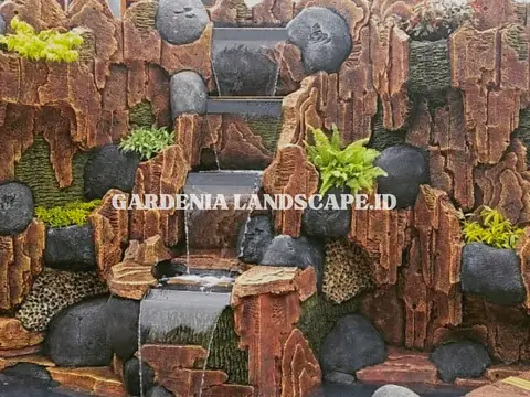 Air terjun dari susunan batu dengan tanaman paku