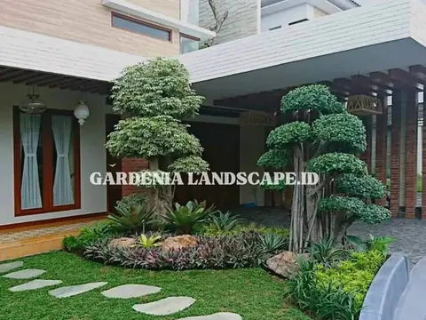 Taman depan rumah dengan dua pohon bonsai besar dan batu pijakan