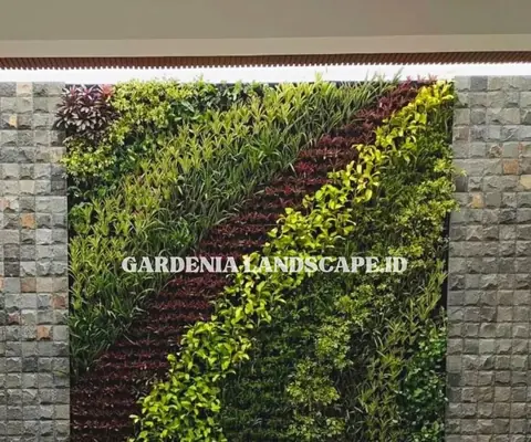 Dinding tanaman berpola diagonal hijau dan cokelat kemerahan di dinding batu