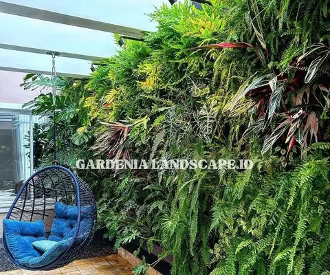 Dinding tanaman rimbun di samping kursi gantung biru